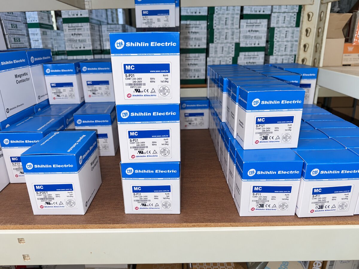 Blue and white Shihlin Electric contactor boxes stacked on shelves, with green and white boxes marked 4 Poles behind