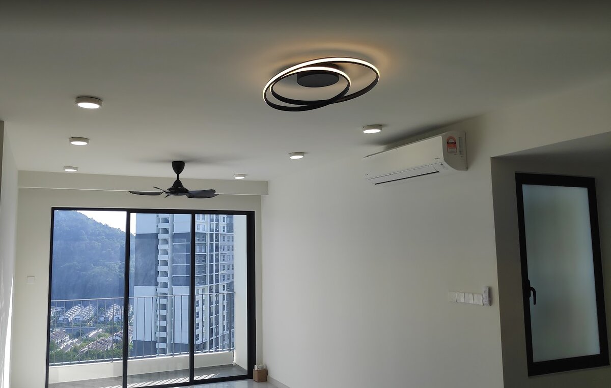 Empty condominium living room with a black double-ring ceiling light, recessed downlights, a ceiling fan and a wall air conditioner beside sliding glass doors