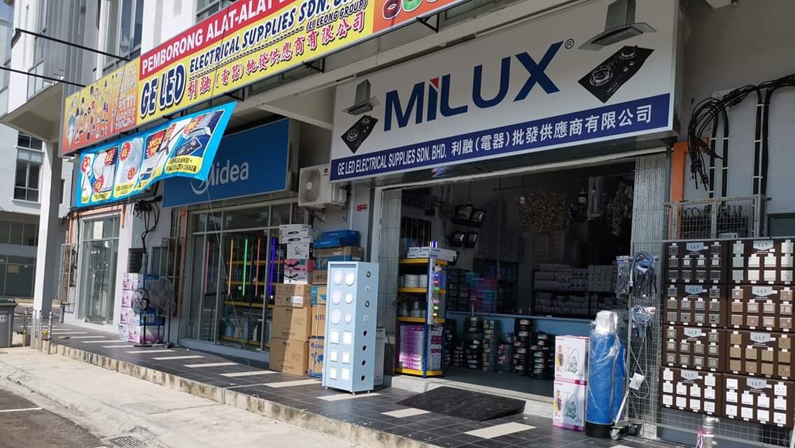 Shopfront with a yellow GE LED Electrical Supplies signboard, a Milux sign, and boxes and wall-plate display boards on the walkway