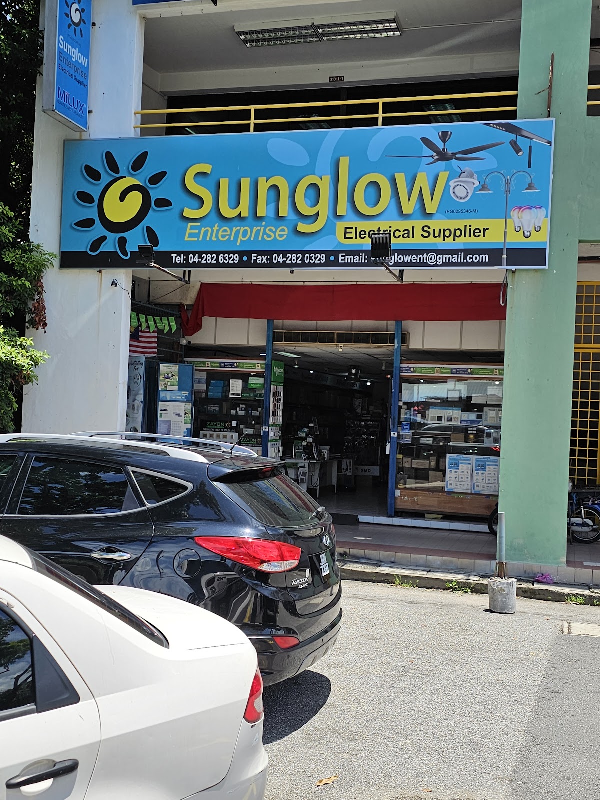 Shoplot with a blue signboard reading Sunglow Enterprise Electrical Supplier with phone, fax and email, and an open shopfront displaying lights
