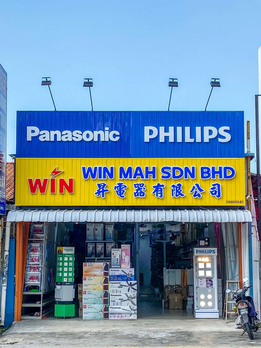 Shop front with a blue Panasonic and Philips sign above a yellow WIN MAH SDN BHD signboard, shelves of goods inside