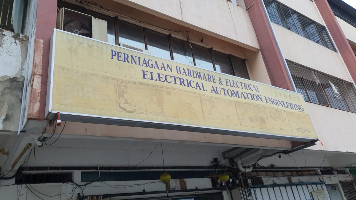Faded yellow shop signboard reading Perniagaan Hardware & Electrical, Electrical Automation Engineering
