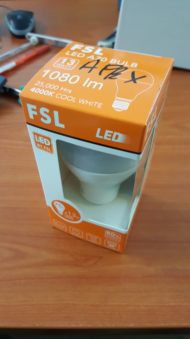 Orange FSL LED bulb box with APEX written on it in marker, on a wooden desk