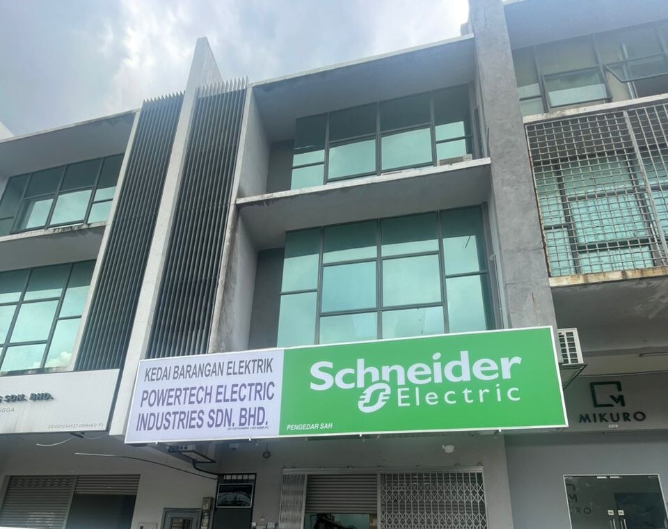 Three-storey shop office with a white fascia reading Powertech Electric Industries Sdn Bhd beside a green Schneider Electric panel