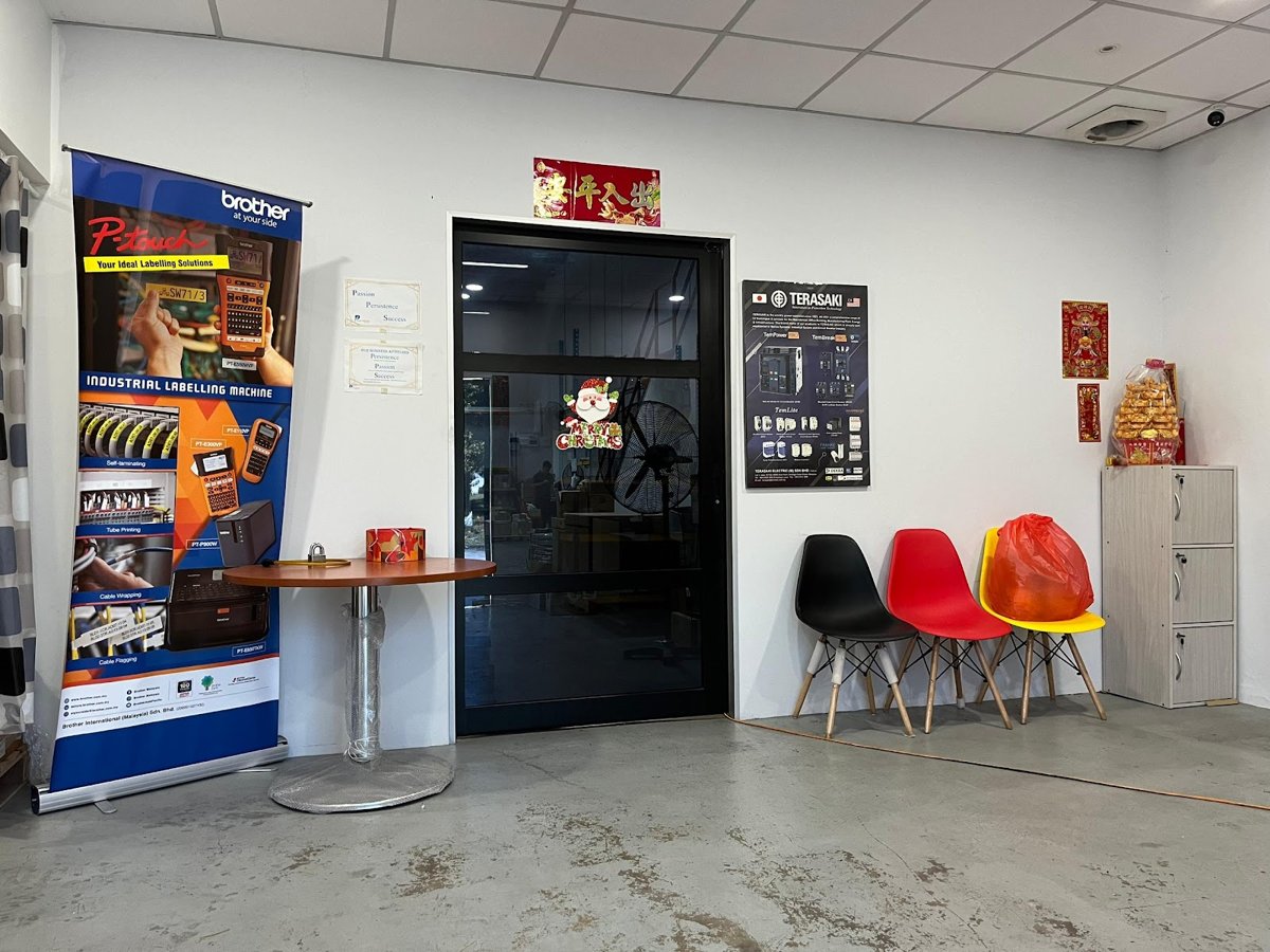 Reception area with a Brother P-touch labelling-machine pull-up banner, a Terasaki poster on the wall and three chairs