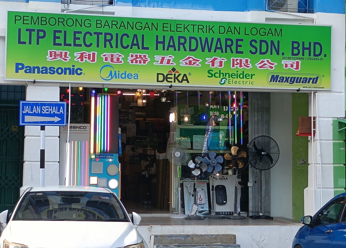 Green LTP Electrical Hardware Sdn Bhd signboard with brand logos above a glass shopfront with standing fans, water-heater boxes and a lighting display