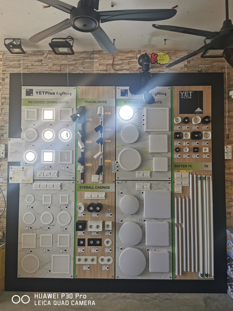 Illuminated display board of square and round LED downlights, tracklights and LED battens under ceiling fans