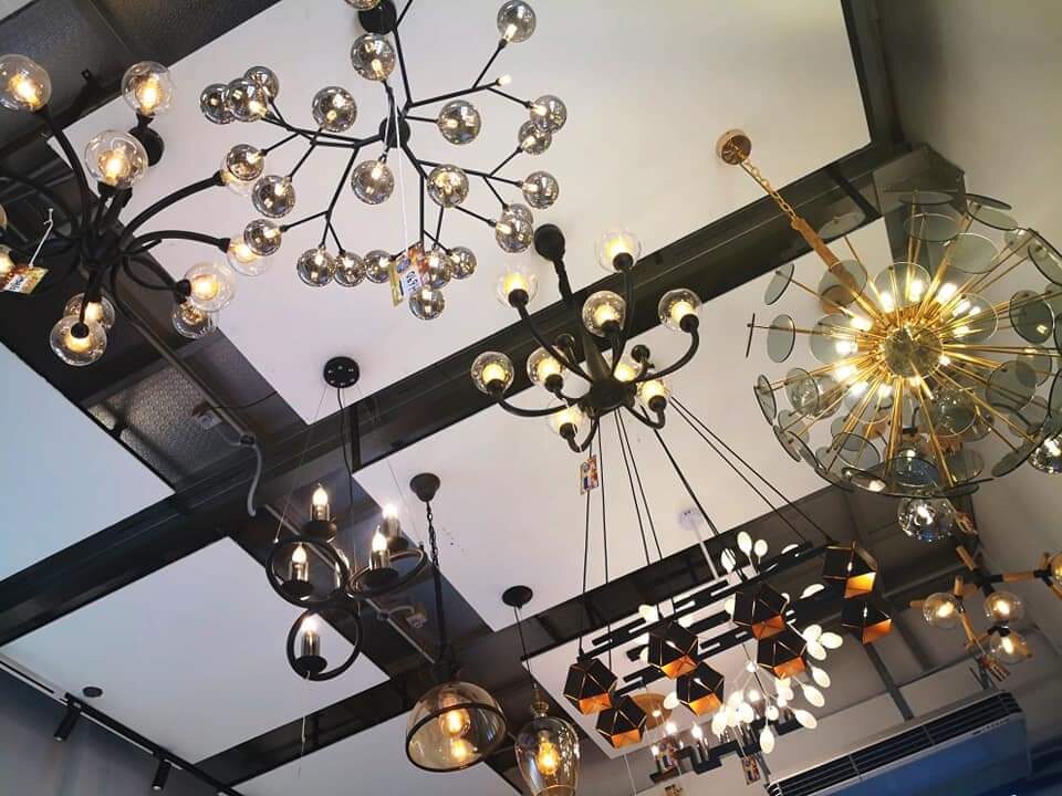 Ceiling hung with black branch chandeliers with smoked glass globes, a gold starburst chandelier and smaller pendant lamps