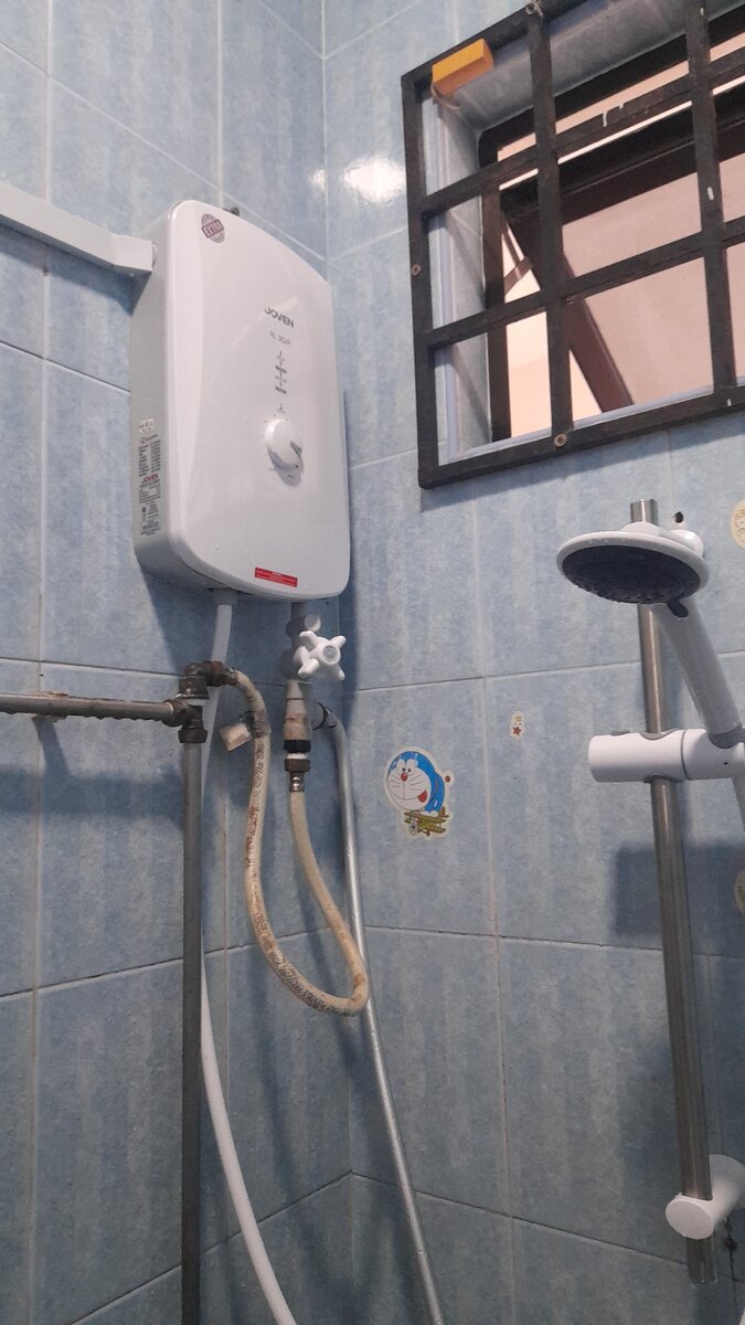 Instant water heater mounted on a tiled bathroom wall with a shower set