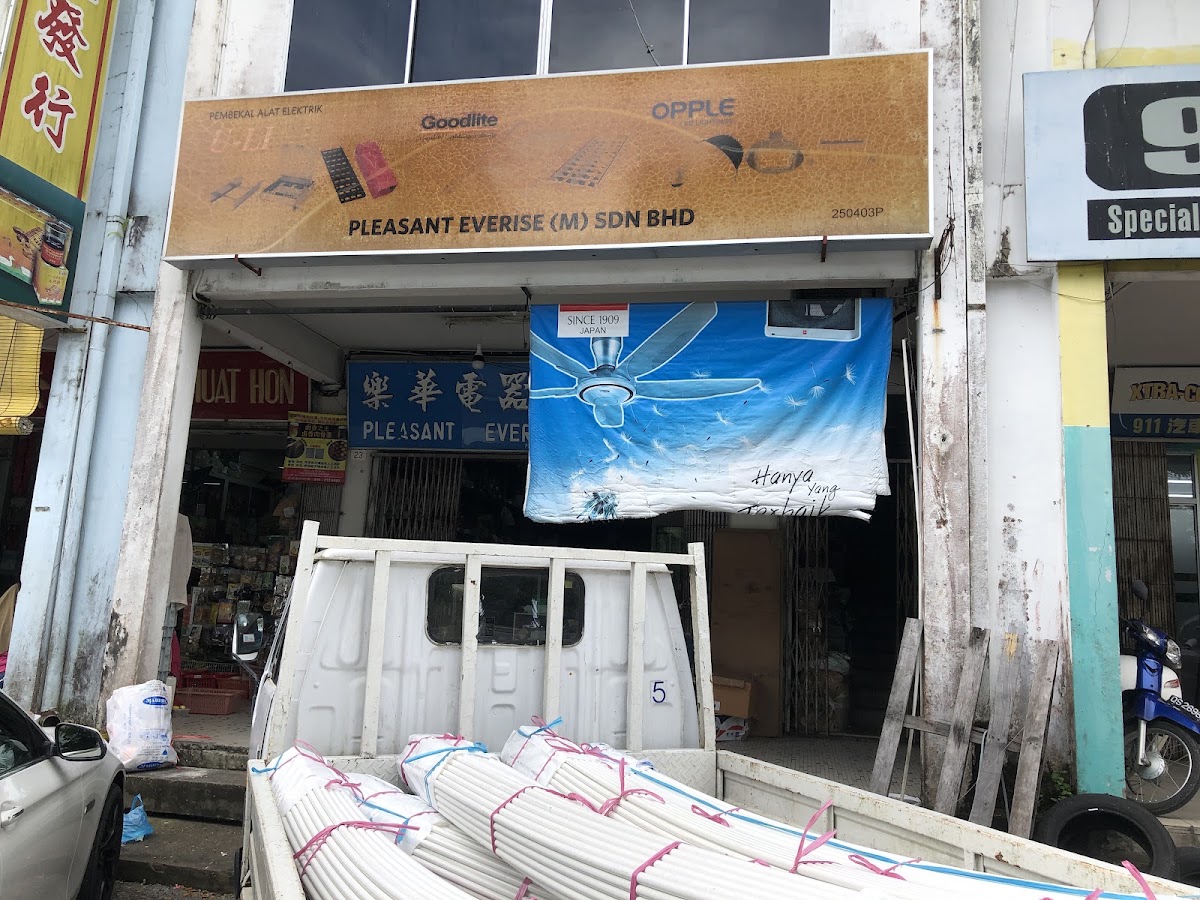 Shoplot with a gold signboard reading Pleasant Everise (M) Sdn Bhd with Goodlite and Opple logos, a ceiling-fan banner and a lorry carrying white PVC conduit