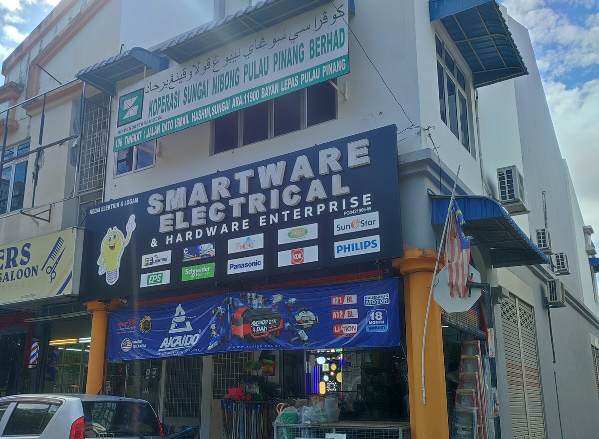 Corner shophouse with a dark blue Smartware Electrical signboard carrying brand logos, an Akaido banner and brooms and ladders at the entrance