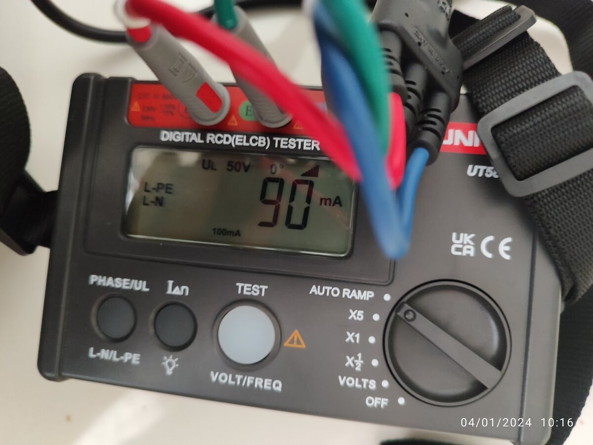 Close-up of a grey and red digital RCD tester with red, green and blue test leads, its display reading 90 mA