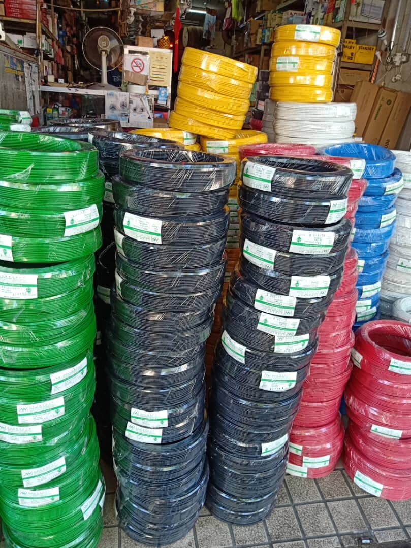 Tall stacks of plastic-wrapped cable coils in several colours in front of a shop counter