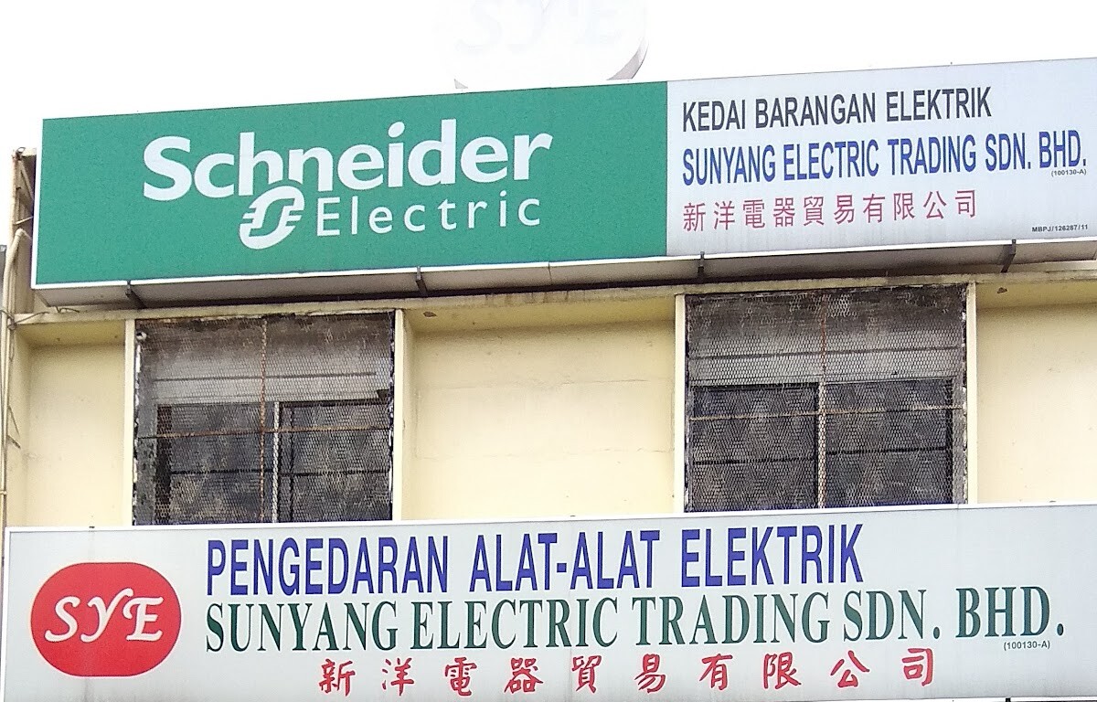 Green Schneider Electric sign beside a white Kedai Barangan Elektrik Sunyang Electric Trading panel, above the Pengedaran Alat-Alat Elektrik signboard