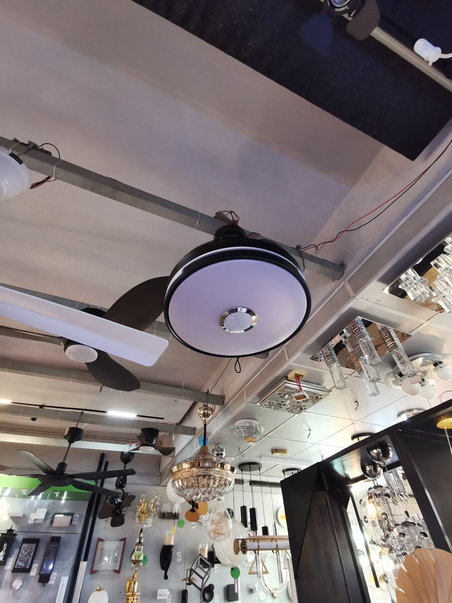 Shop ceiling hung with a ceiling fan with a round LED light, chandeliers and wall-mounted fittings below
