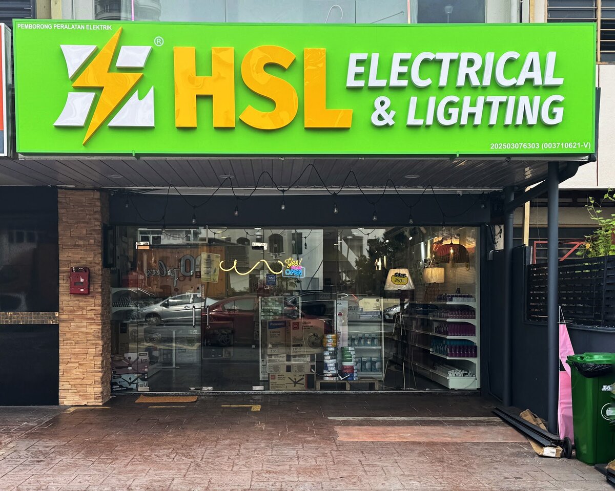 Glass shopfront under a bright green HSL ELECTRICAL & LIGHTING signboard with a yellow lightning-bolt logo; shelves and lamps are visible inside