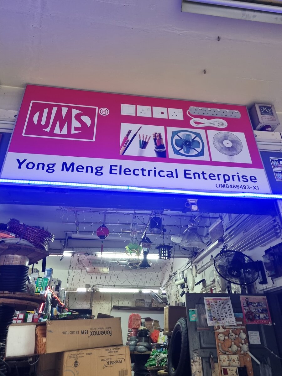 Pink UMS signboard reading Yong Meng Electrical Enterprise above an open shopfront with cable reels, boxes and hanging lights