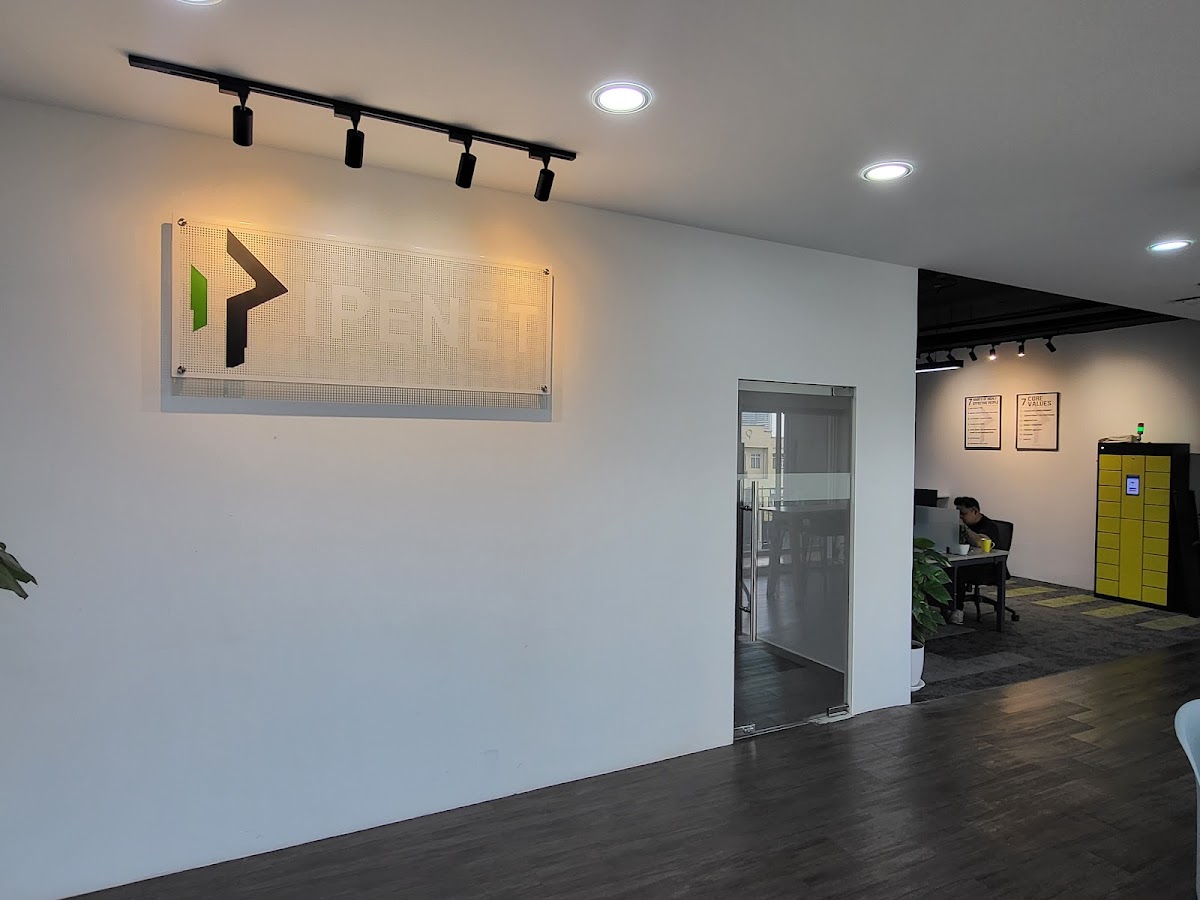 Office reception wall with a spot-lit Ipenet logo panel, track lights and a glass door
