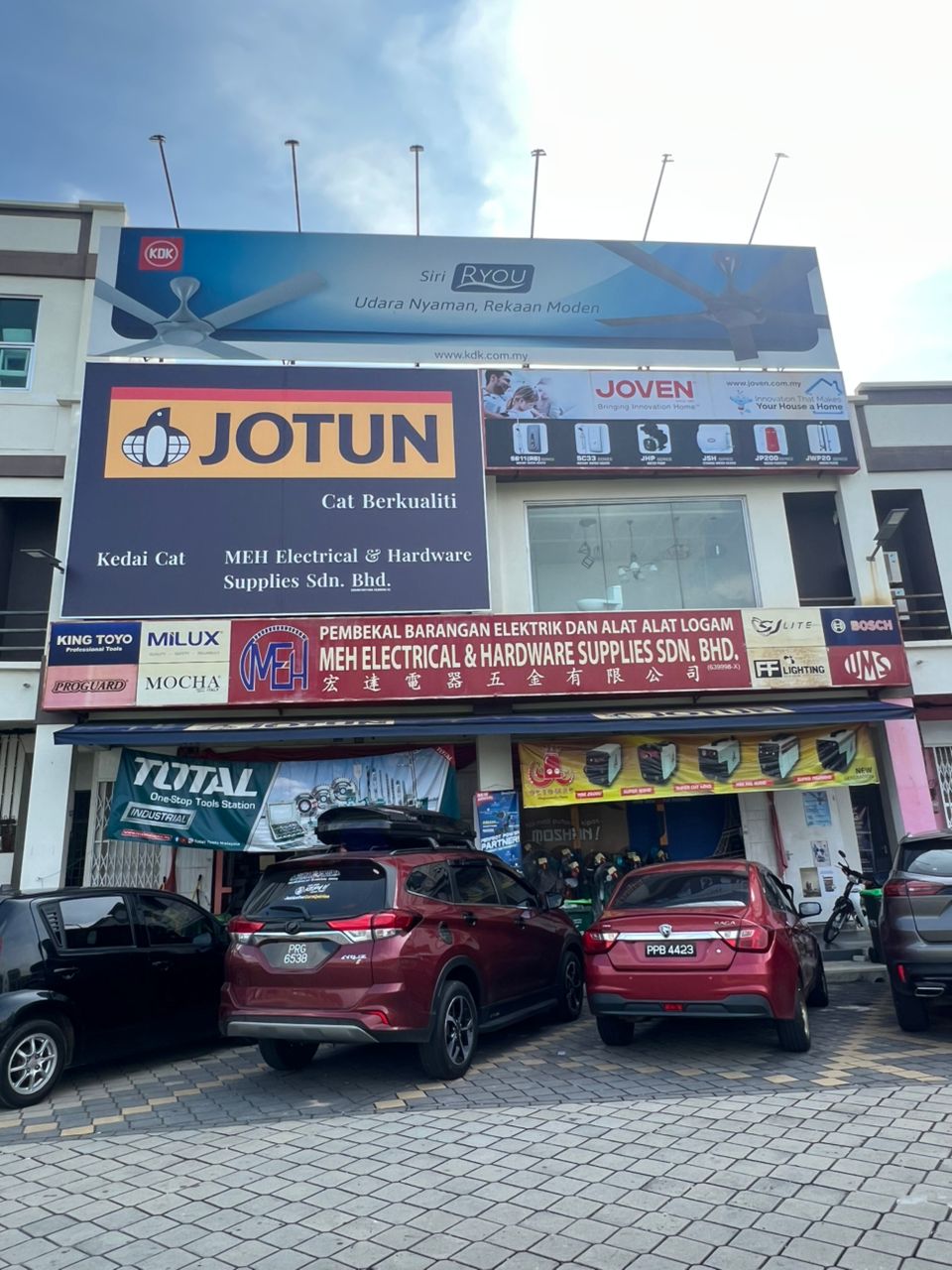 Shoplot with a large Jotun Kedai Cat sign, a KDK billboard and an MEH Electrical & Hardware Supplies signboard with brand logos