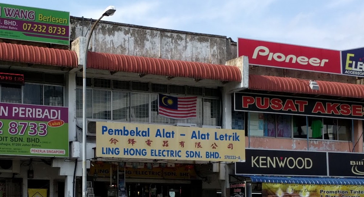 Yellow shop signboard reading Pembekal Alat-Alat Letrik and Ling Hong Electric Sdn. Bhd. on a shophouse row, between a moneylender sign and car-accessory shop signs