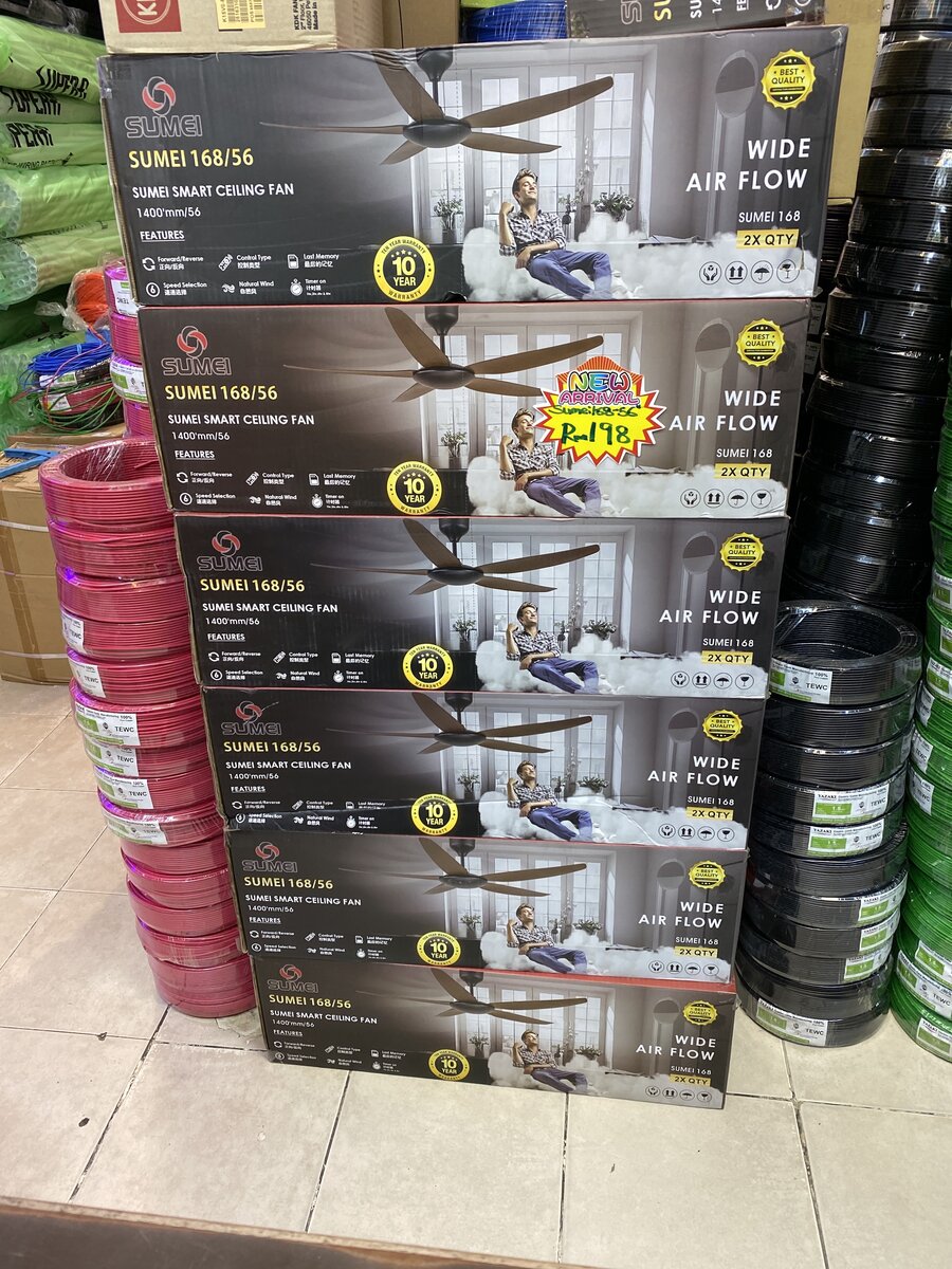 A stack of six boxed Sumei ceiling fans between columns of red, black and green wire coils, with green-wrapped conduit bundles behind