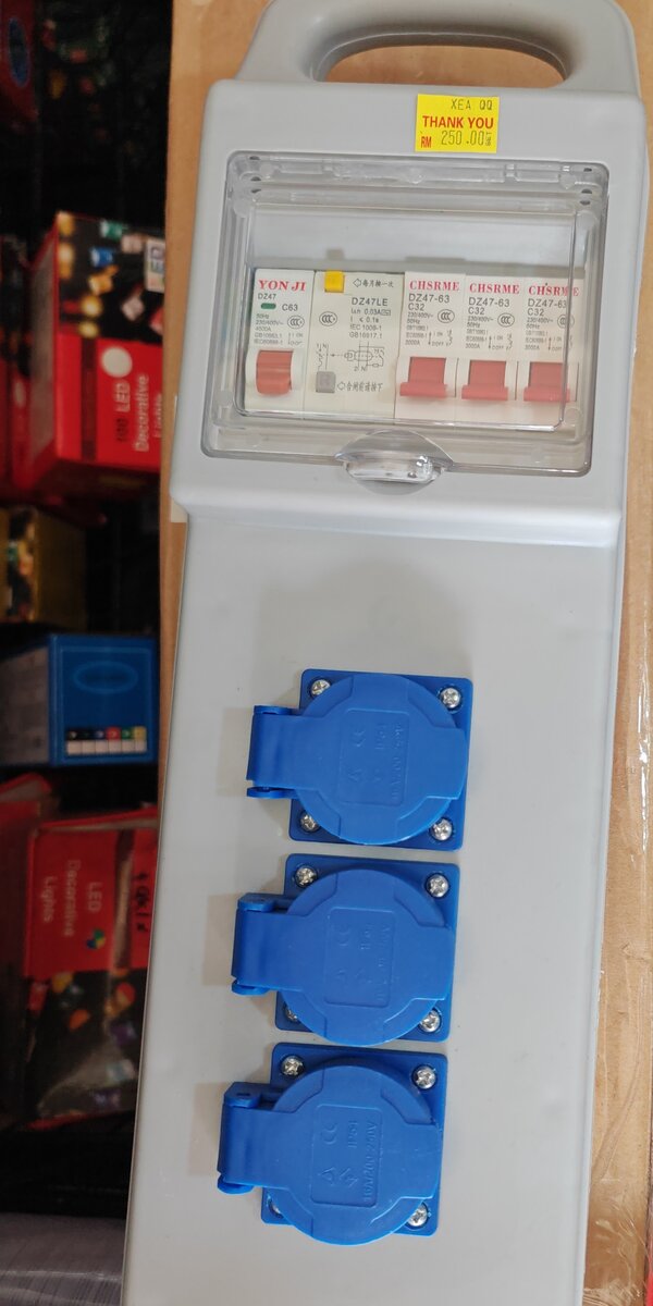 Grey portable power box with a clear window over a row of breakers and three blue lidded sockets