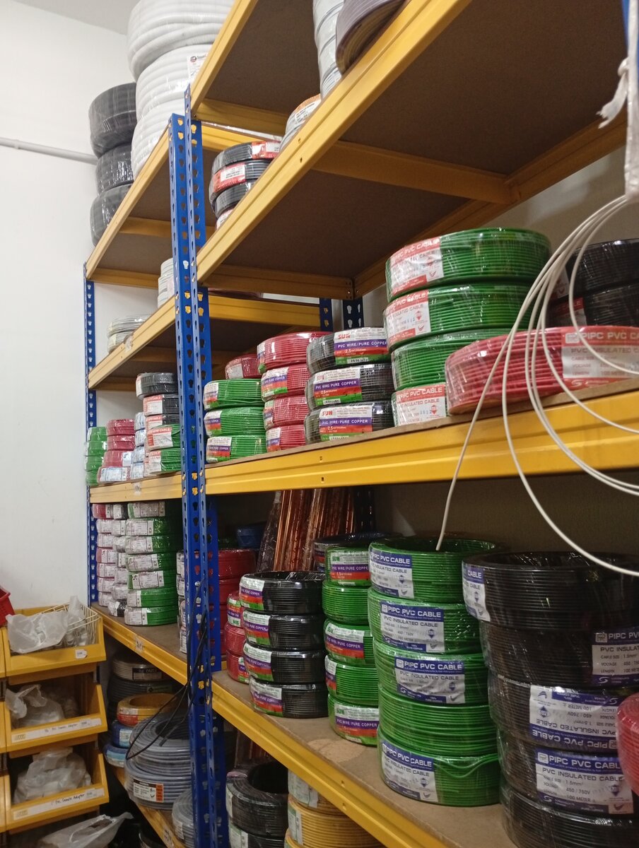 Shelves stacked with green, red and black coils of PVC-insulated wire, with white and black conduit coils on the top shelves