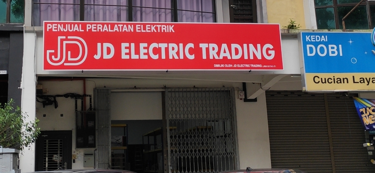 Red JD Electric Trading signboard over a shuttered shop unit