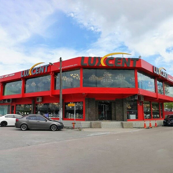 Red single-storey corner showroom with large Luxcent signs and chandeliers visible through the glass