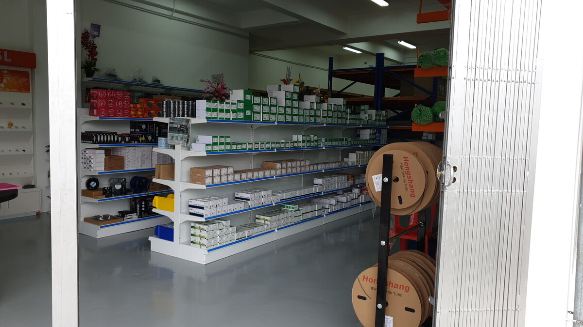 Shop shelves stacked with boxed electrical accessories beside cable-reel racks