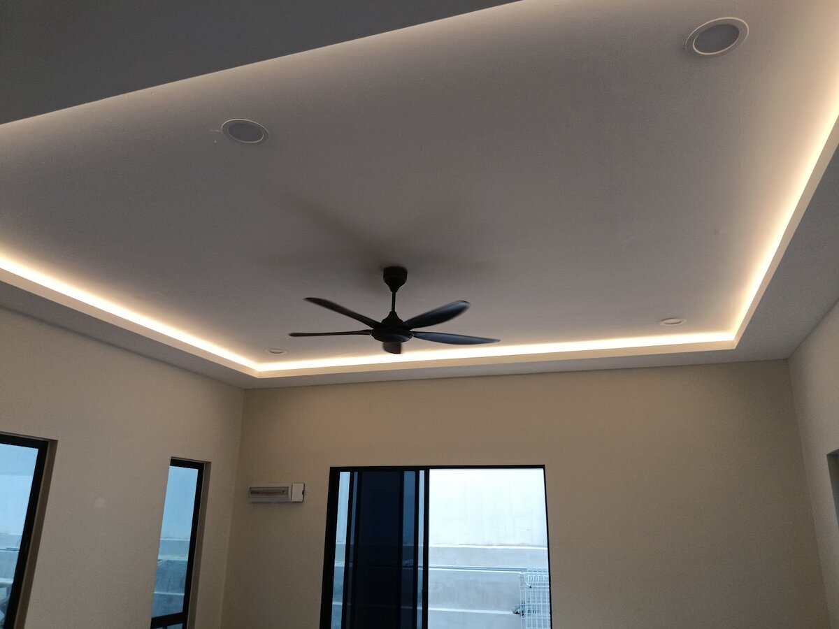 Living room ceiling with warm LED cove lighting around a recessed panel, downlights and a black five-blade ceiling fan