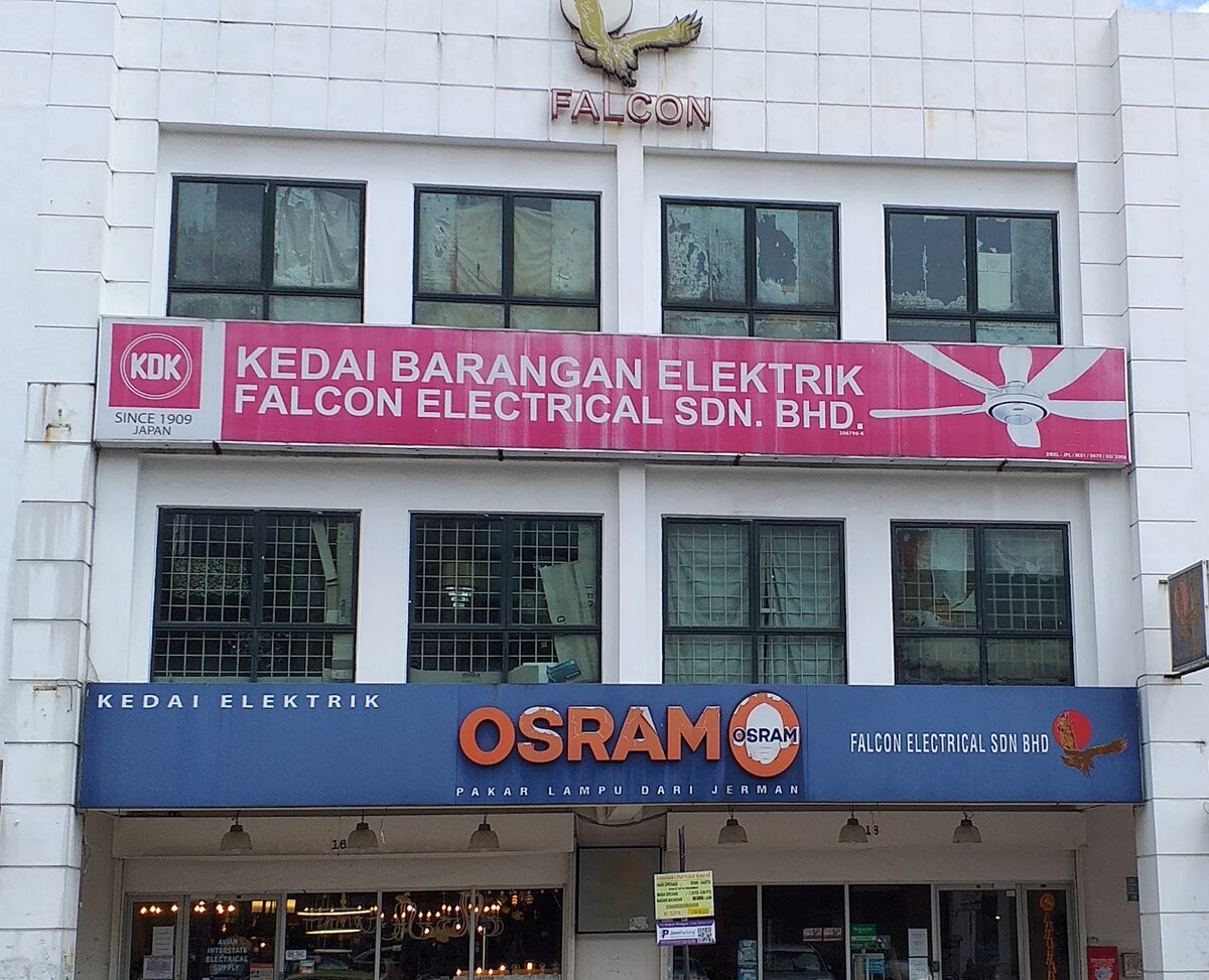 White three-storey shophouse with a falcon emblem, a pink KDK signboard and a blue Osram signboard reading Falcon Electrical Sdn Bhd