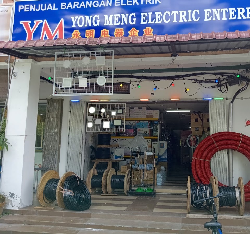 Electrical shopfront under a blue 'Yong Meng Electric Enterprise' signboard, with cable drums, a coil of red conduit and LED floodlights on wire racks