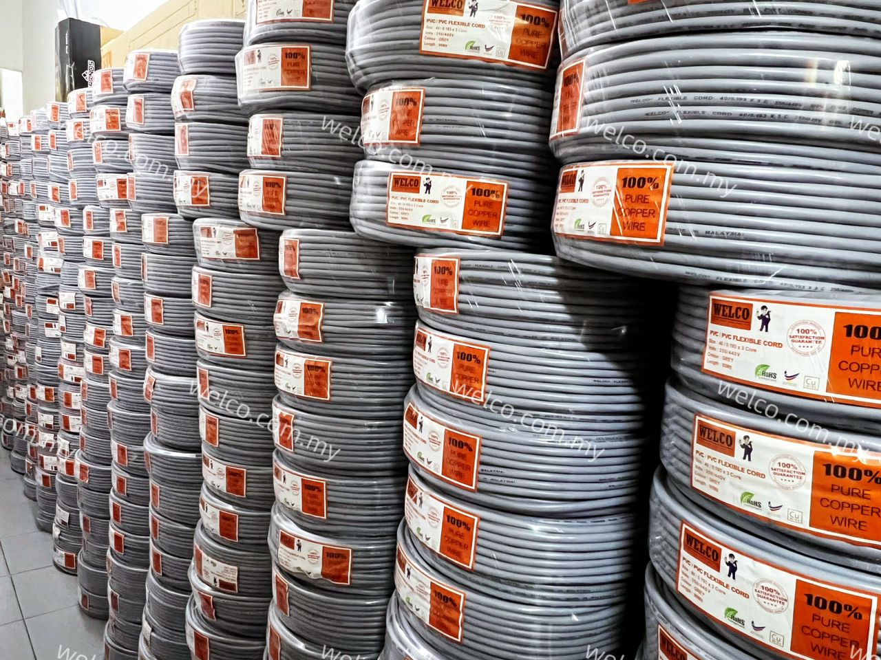 Stacks of grey cable rolls with orange Welco labels reading 100% pure copper wire