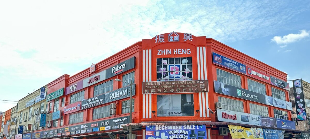 Orange three-storey corner building with a "Zhin Heng" sign and Rubine, Joven, Senz, Robam, Nippon Paint, MCI and Rinnai signboards
