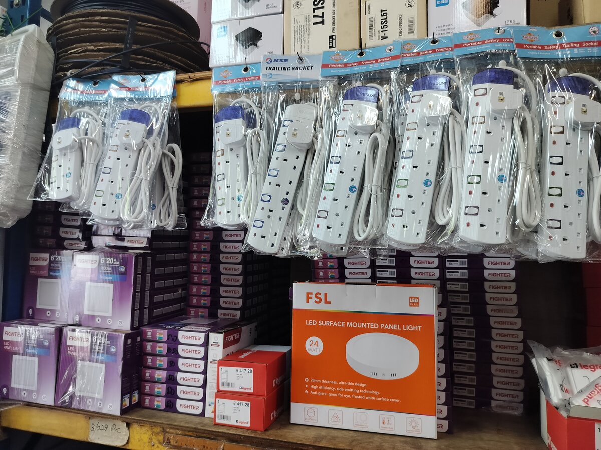 Row of white trailing socket extension leads in plastic bags hanging above purple Fighter LED panel boxes and an orange FSL LED panel box