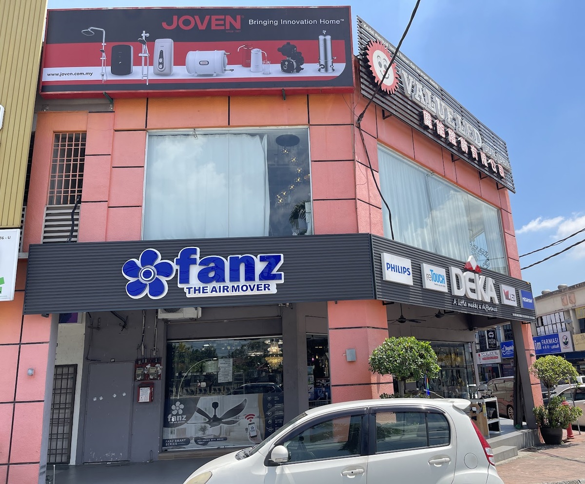 Pink corner shop with a large Value LED sign, a blue Fanz fan sign and a row of brand logos above the entrance