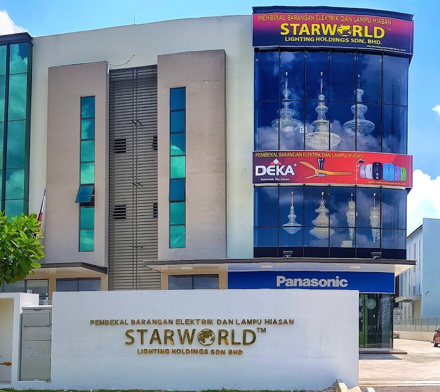 Three-storey glass-fronted building with Starworld, Deka and Panasonic signs and a white Starworld Lighting Holdings boundary wall