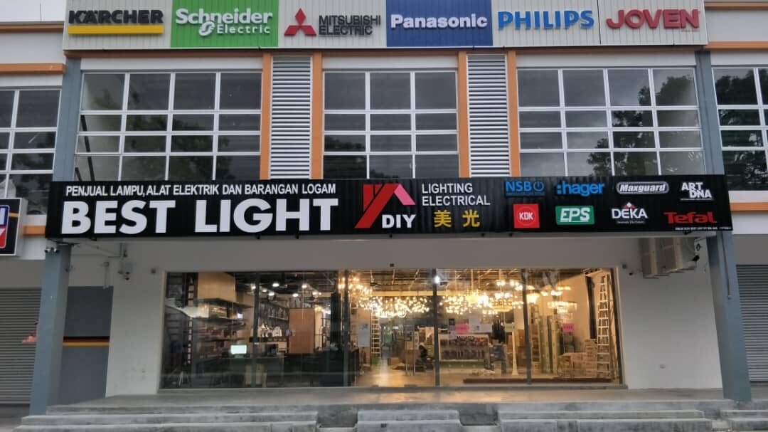 Two-storey shop front with a black Best Light DIY signboard, a row of brand logos above and a lit chandelier showroom behind the glass