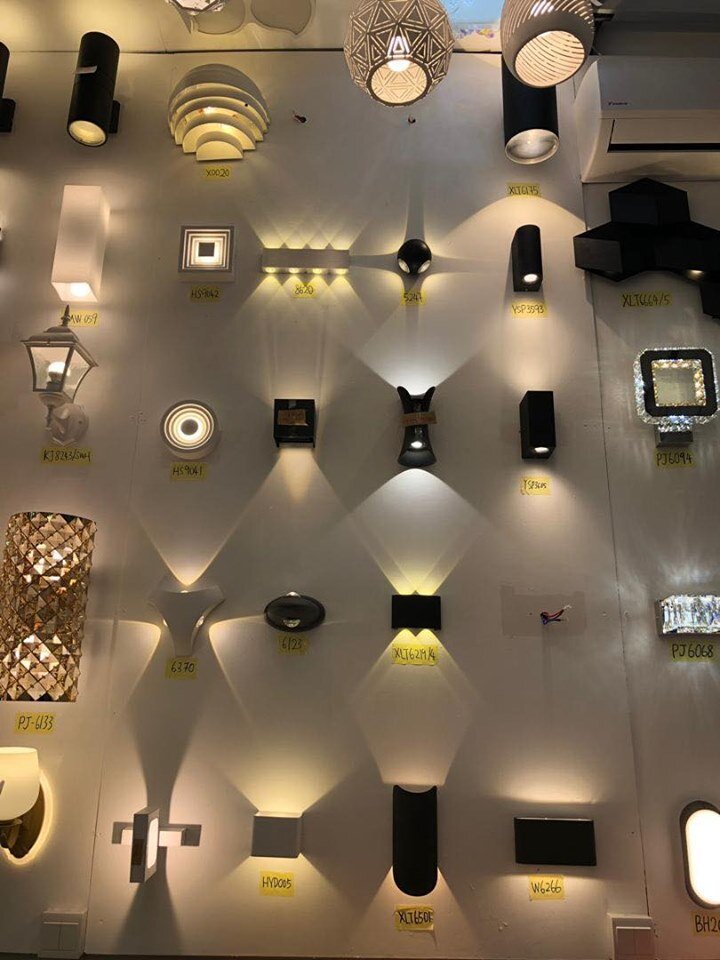 Display wall of lit indoor and outdoor wall lights casting up-and-down light patterns