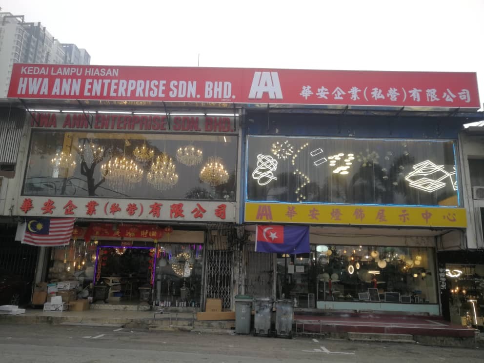 Two shop units under a long red signboard reading Kedai Lampu Hiasan, Hwa Ann Enterprise Sdn. Bhd., with chandeliers and LED ring lights in the windows