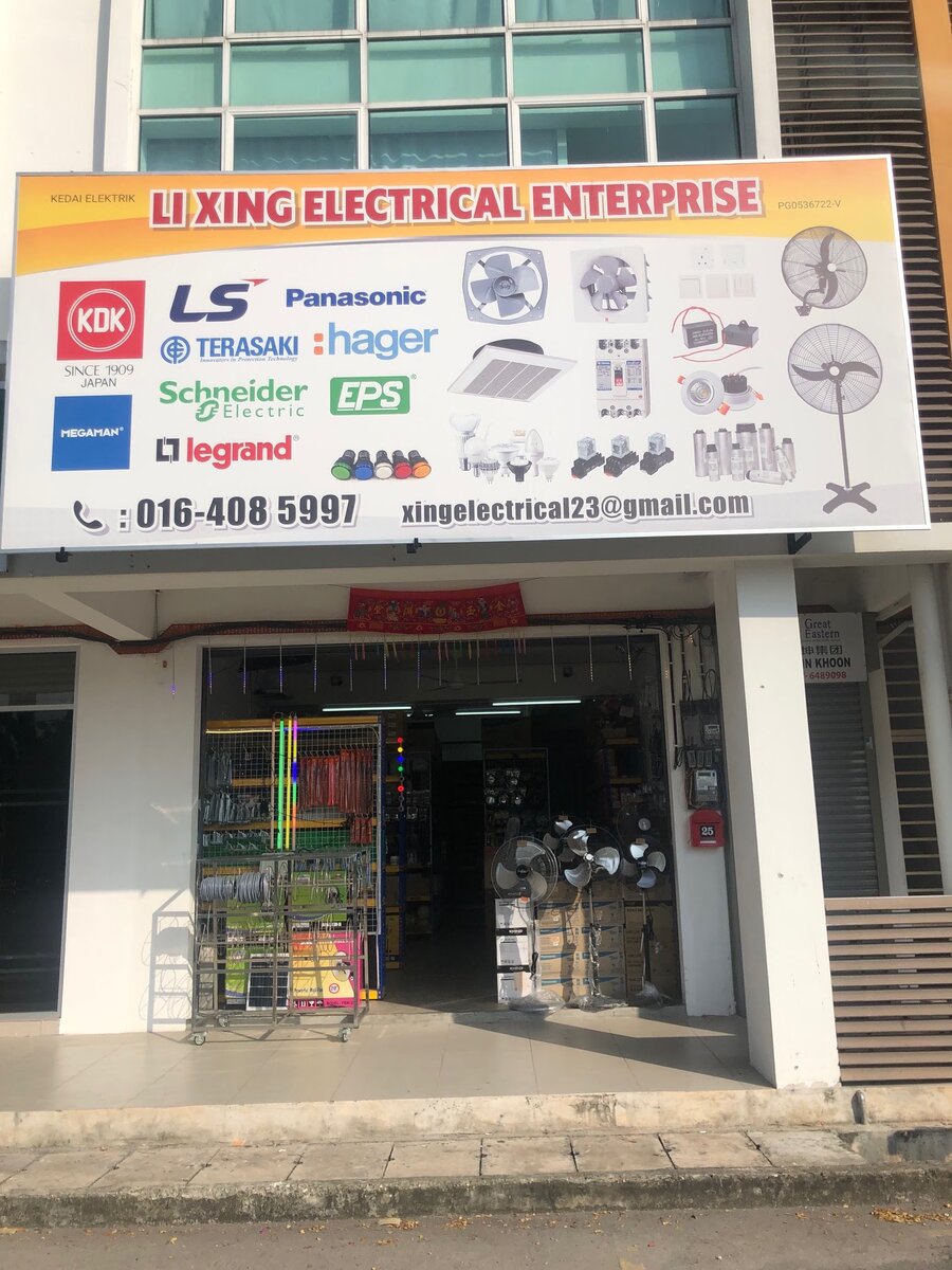 Shophouse with a large Li Xing Electrical Enterprise signboard showing brand logos, fans and electrical parts, phone 016-408 5997, and an open shopfront with racks of goods