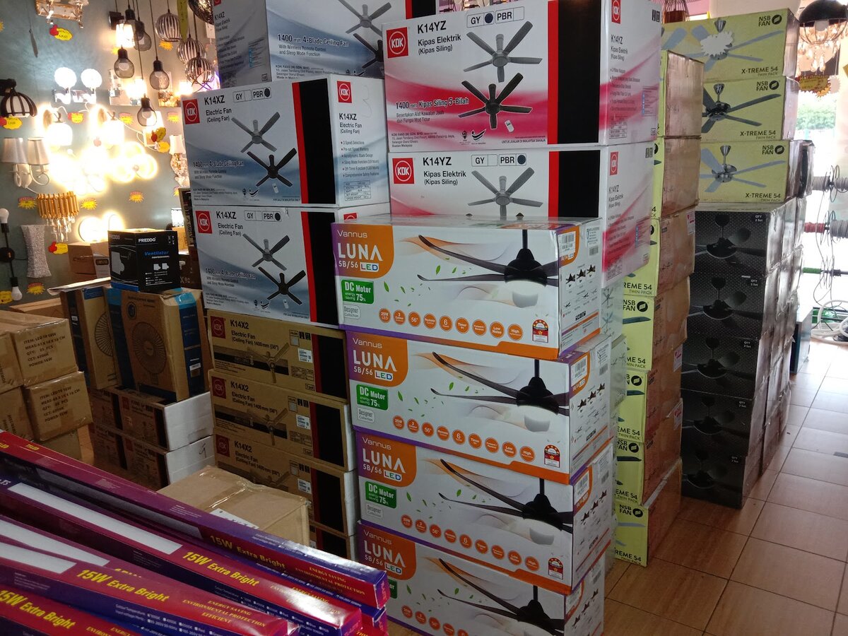 Stacks of boxed ceiling fans with KDK and Vannus Luna packaging in front of a lighting display