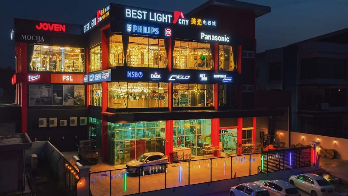 Corner three-storey building at night with Best Light City and Chinese signage, Philips and Panasonic logos, and windows full of glowing chandeliers