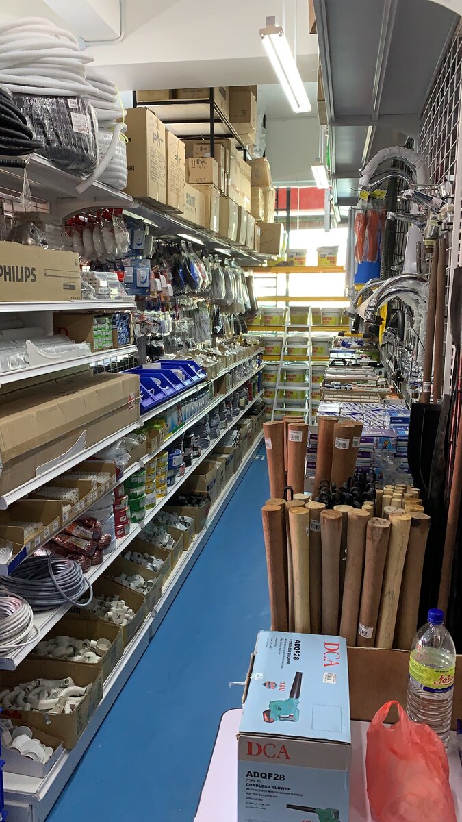 Shop aisle with coils of flexible conduit on the top shelf, Philips lamp boxes, coloured wire coils and bins of white PVC conduit fittings