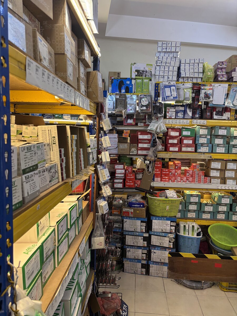 Shelves stacked with boxed Hager, EPS and Schneider wiring devices beside racks of sockets, meters and lamp holders