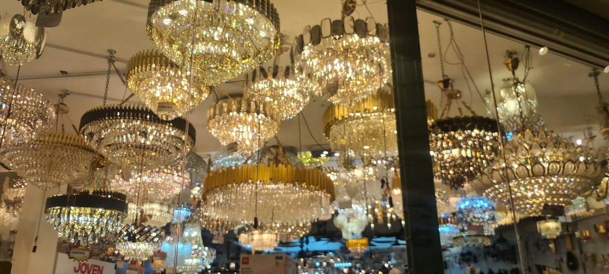Ceiling crowded with gold and crystal chandeliers lit up in a lighting showroom