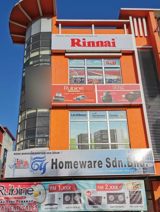 Orange four-storey shop building with Rinnai, Rubine and SENZ signs and a "FY Homeware Sdn. Bhd." signboard above a sale banner