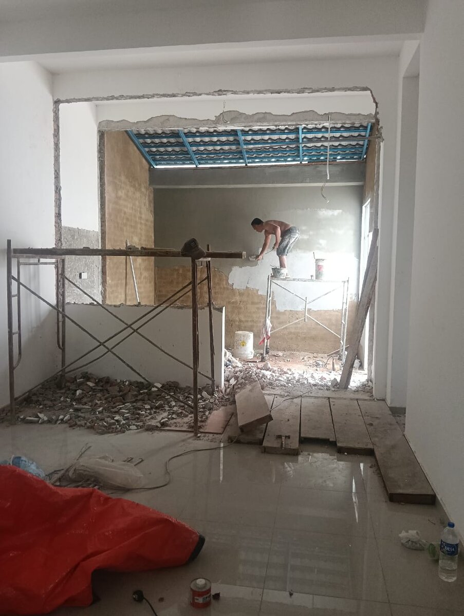 Room interior with scaffolding, rubble on the floor and a worker plastering an opened wall