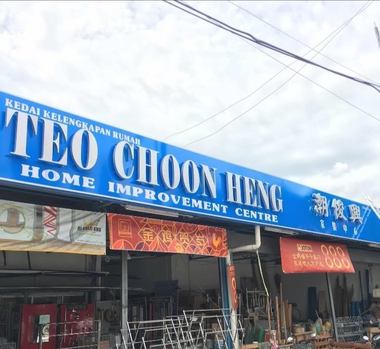 Blue fascia reading Kedai Kelengkapan Rumah, Teo Choon Heng, Home Improvement Centre, with red Chinese banners and racks of goods at the open front